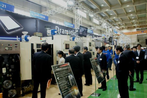 新工場で使用する新しい機械を見学するたくさんの人々の写真